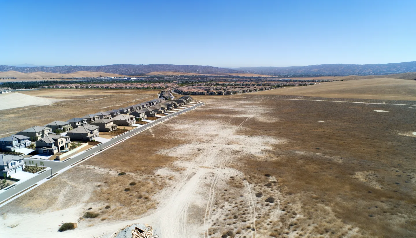 Aerial view of undeveloped land next to new construction in California