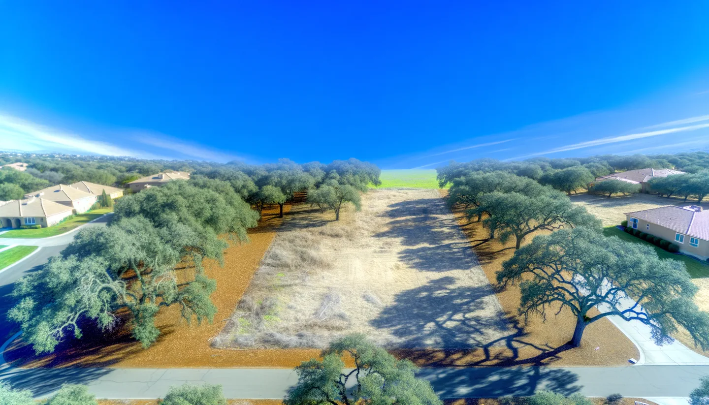 Aerial view of a cleared vacant lot bordered by oak trees in California
